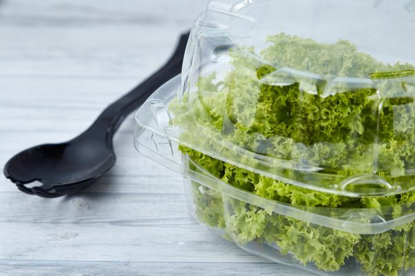 Recipiente plástico con ensalada encima